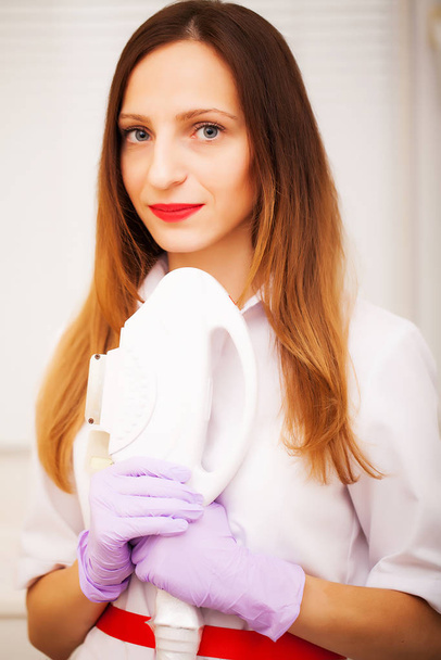 Woman doctor displaying machine for laser hair removal - Fotó, kép