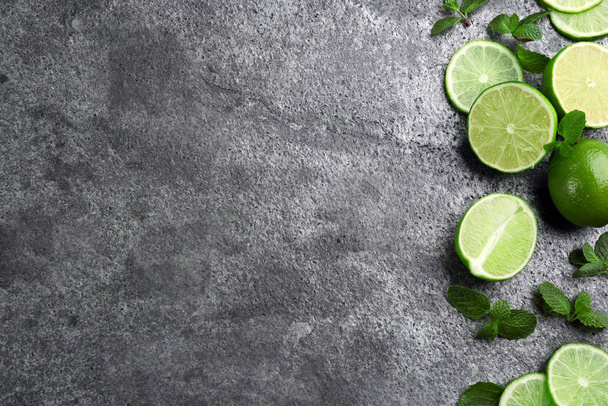 Lemonade layout with juicy lime slices and mint on grey table, top view. Space for text - Foto, imagen
