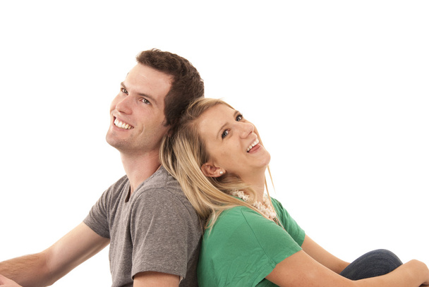 junges Paar sitzt Rücken an Rücken und blickt nach oben - Foto, Bild