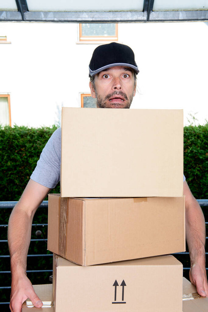 overstrained postman with parcels and dark cap - Photo, image
