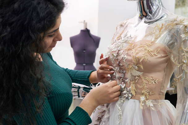 Dressmaker fijación vestido de novia de encaje blanco en un maniquí en el estudio de sastrería
 - Foto, Imagen