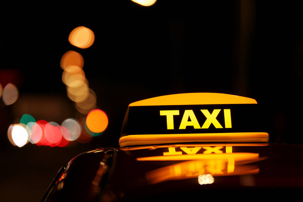 Taxi car with yellow roof sign on city street at night, closeup - Photo, Image