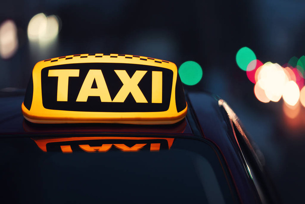 Taxi auto se žlutou střechou na ulici města ve večerních hodinách, detailní záběr - Fotografie, Obrázek