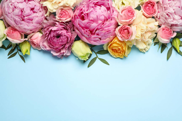 Flat lay composition with beautiful flowers and space for text on light blue background. Floral card design - Foto, imagen