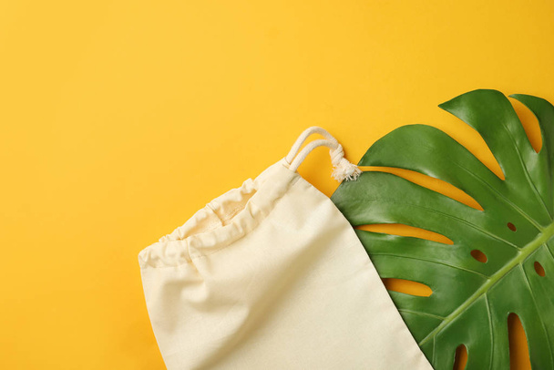 Cotton eco bag and leaf on yellow background, flat lay. Space for text - Fotoğraf, Görsel