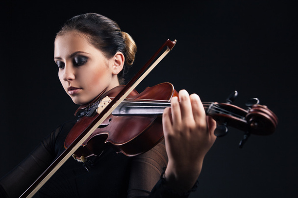 Beautiful young woman playing violin over black - Photo, Image