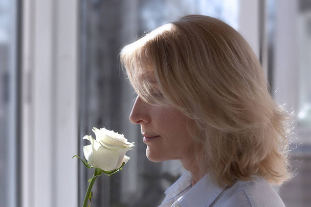 Blondynka w średnim wieku z białym kwiatem róży zbliżenie - Zdjęcie, obraz