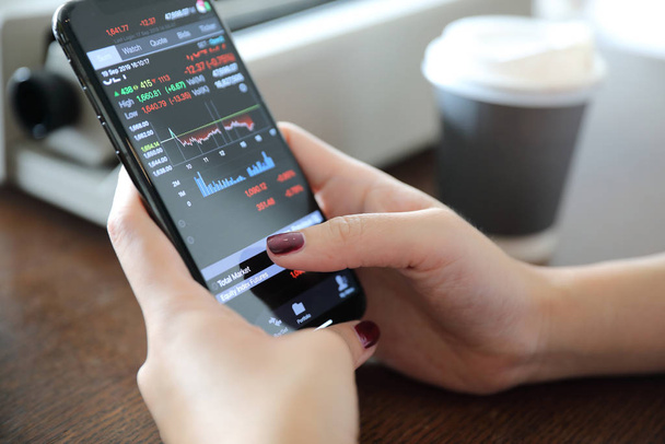 Main féminine avec smartphone trading stock en ligne dans le café
  - Photo, image