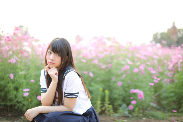 Retrato de uniforme de niña de escuela japonesa con flor de cosmos rosa - Foto, imagen