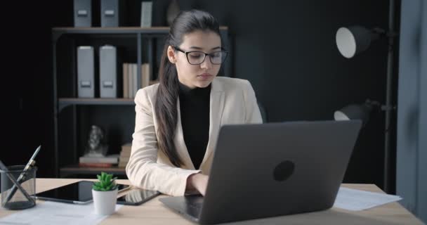 Portré komoly lány használó laptop a modern irodában - Felvétel, videó