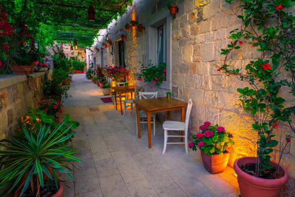 Harmonious narrow street and street cafe decorated with flowers - Photo, Image