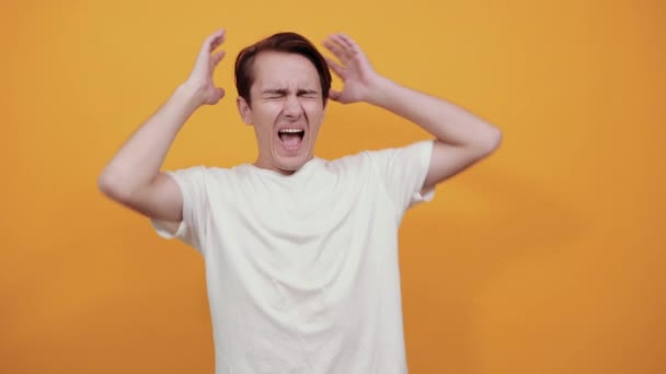 Um jovem de t-shirt branca grita com as mãos atrás da cabeça
  - Filmagem, Vídeo