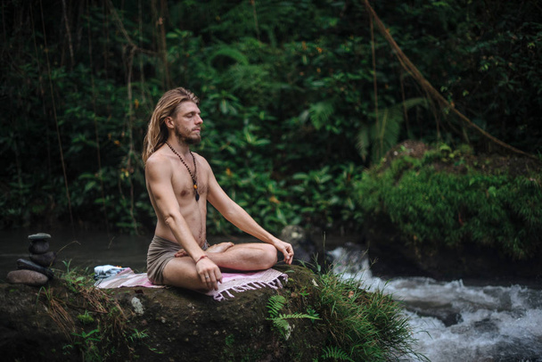 Práctica de yoga y meditación en la naturaleza. Hombre practicando cerca del río
 - Foto, Imagen