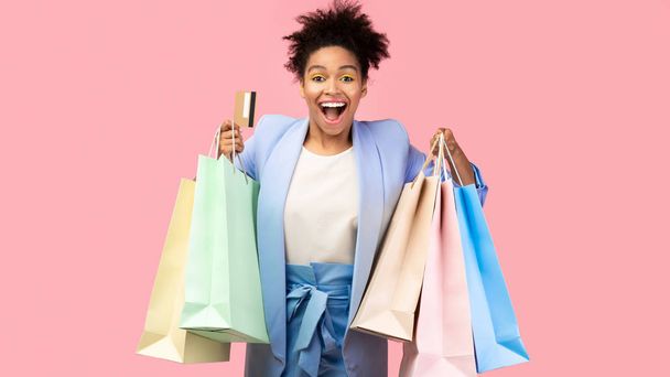 Mulher negra alegre com sacos de compras e cartão de plástico
 - Foto, Imagem