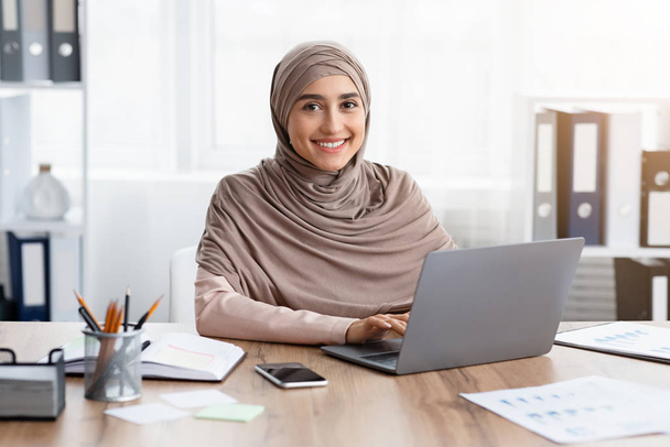 Portrait of happy muslim female office employee at workplace in office - Photo, Image