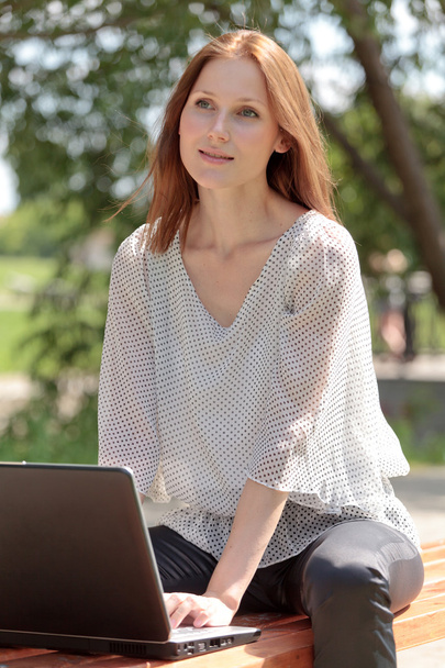 Pretty young woman with a laptop at park - Photo, Image