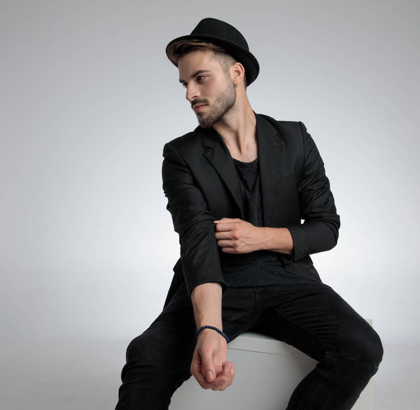 cool fashion guy wearing hat and holding elbow in a fashion pose - Foto, Bild