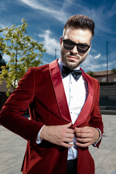 arrogant young elegant man arranging red velvet coat - Fotoğraf, Görsel
