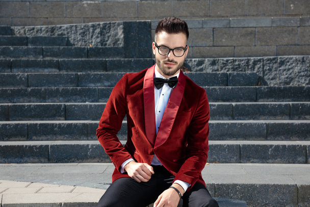 smart casual man in red velvet tuxedo sitting on stairways - 写真・画像