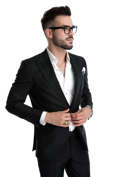 businessman standing and looking aside while fixing jacket serio - Photo, Image