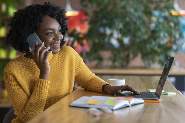 Radosna czarna kobieta rozmawia przez telefon z klientami - Zdjęcie, obraz
