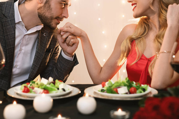 Γενναίος άνθρωπος φιλιά χέρι της κοπέλας του σε ρομαντικό δείπνο στο εστιατόριο - Φωτογραφία, εικόνα