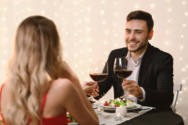 Romantic couple clinking wine glasses during Valentine Day dinner in restaurant - Photo, Image