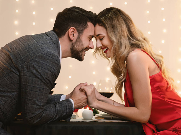 Doce casal apaixonado de mãos dadas durante o jantar romântico no restaurante
 - Foto, Imagem