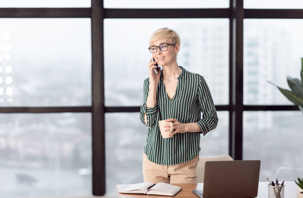 Successful Businesswoman Talking On Phone Standing Near Window In Office - Φωτογραφία, εικόνα