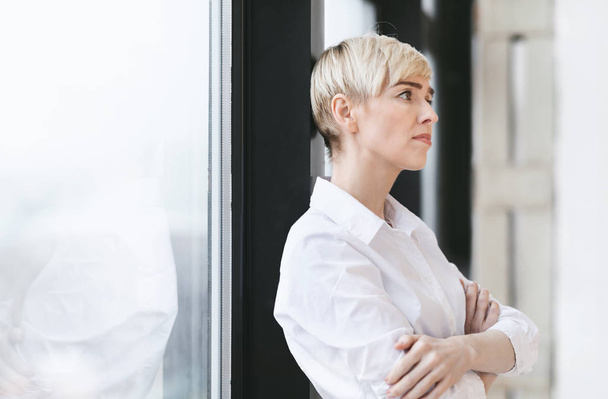 Angst ondernemer vrouw denken staande in de buurt van venster in modern kantoor - Foto, afbeelding