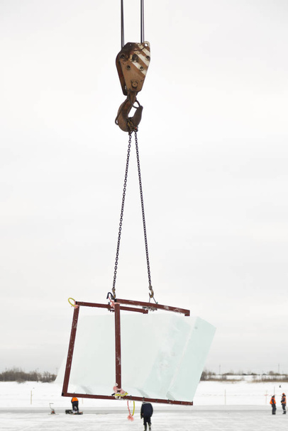 Ciężarowy dźwig podnosi przezroczyste płyty lodu nad rzeką - Zdjęcie, obraz