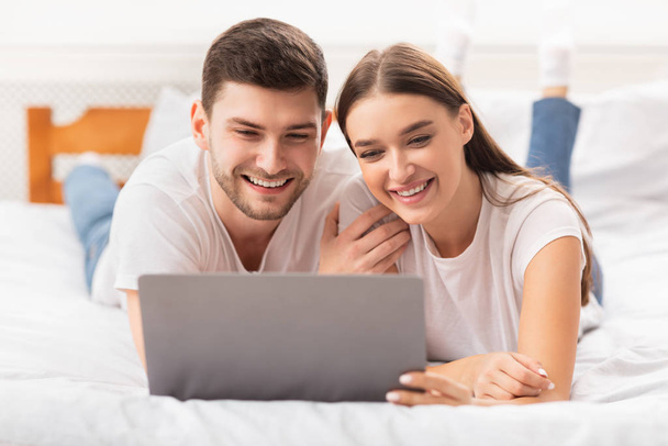 Novio y novia acostado con el ordenador portátil viendo película en el dormitorio
 - Foto, Imagen