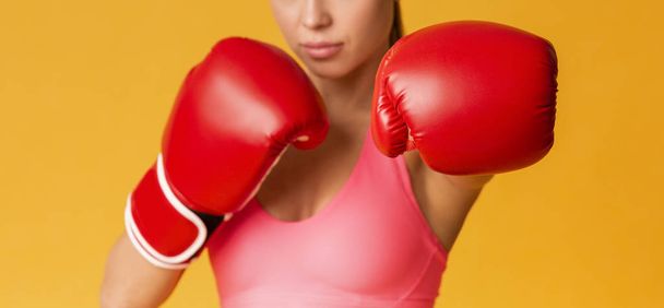 Unerkennbar fitte Frau in roten Boxhandschuhen posiert vor gelbem Hintergrund - Foto, Bild