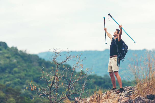 Lifestyle man travel hiker adventure on mountain nature landscape. Young people tourist backpack raise hand after walking trail activity outdoor for destination leisure.  - 写真・画像