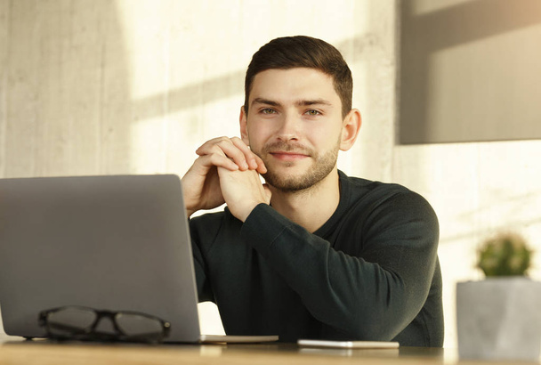 Fiatal férfi a laptopnál ül a munkaasztalnál a Modern Irodában - Fotó, kép
