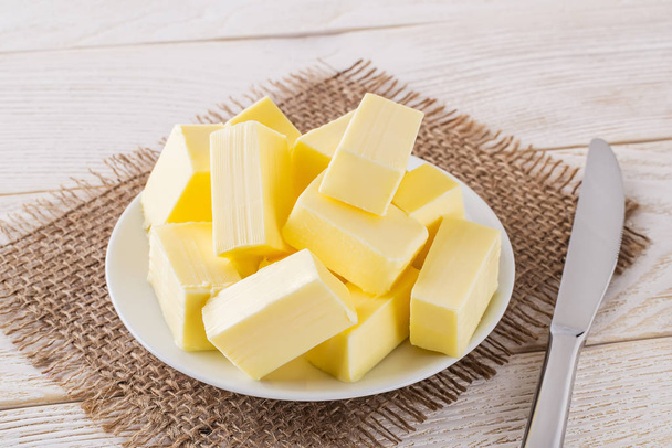 Rectangular pieces of fresh yellow butter on a white saucer - 写真・画像