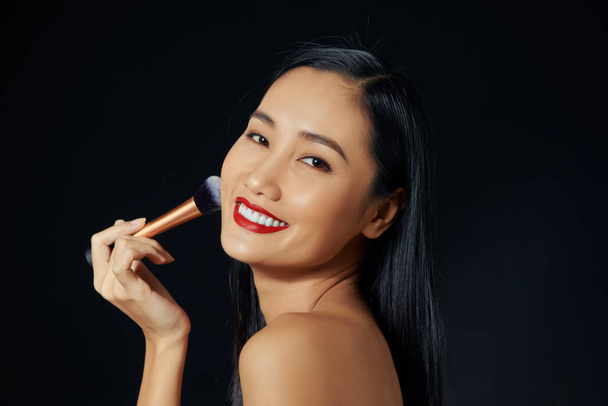 Portrait Of Beautiful Smiling Girl Applying Loose Blush With Cosmetic Brush. - Foto, Imagen