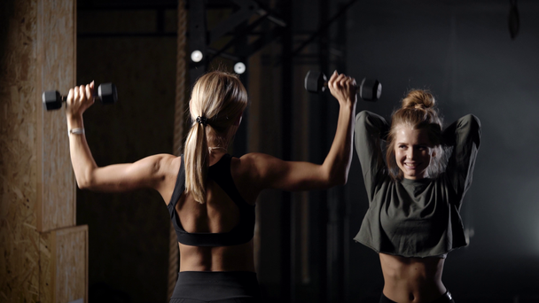 Twee mooie blondjes in de sportschool. Meisjes doen oefeningen met licht gewicht. Het is belangrijk om de gezondheid te controleren en te rekenen. - Video
