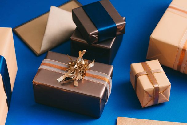Chirsmas concept with gold boxes, envelope, wreath on blue background. - Photo, Image