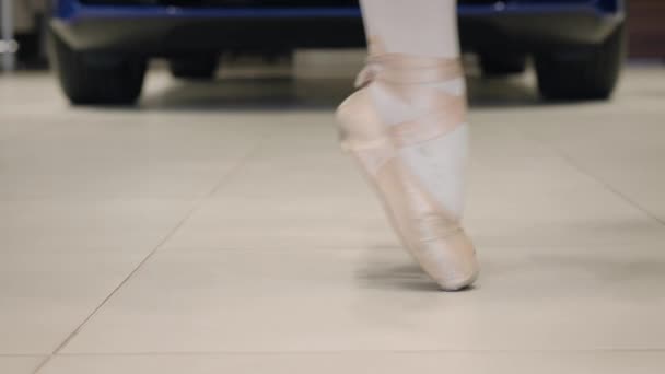 Side view close-up of female feet in pointes balancing on tiptoes. Unrecognizable ballet dancer dancing in car dealership. Automobile industry, art, elegance. - Materiał filmowy, wideo
