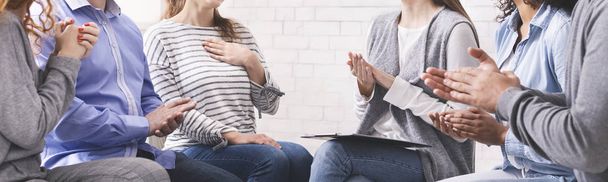 Groep onherkenbare mensen applaudisseert tegen vrouw tijdens psychotherapiesessie - Foto, afbeelding