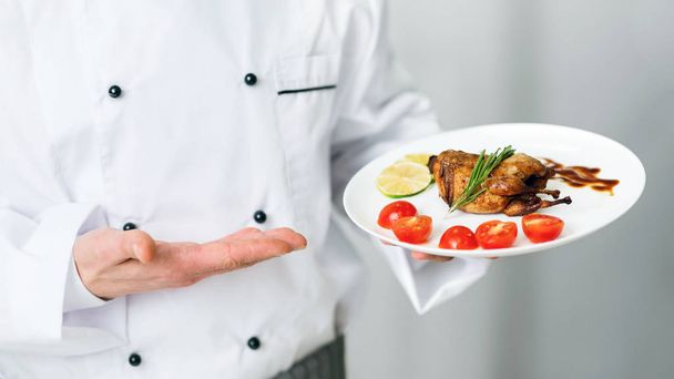 Tunnistamaton kokki tilalla levy paahdettu kana seisoo keittiössä
 - Valokuva, kuva