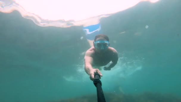 Muscular man in mask swims underwater, holding camera in front. Close-up. - Záběry, video