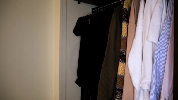 Κοντινό πλάνο των ρούχων στην ντουλάπα κοντά στο λευκό τοίχο. Έννοια. Πλευρική άποψη των διαφόρων πουκάμισα σε πλήρη ντουλάπα, λεπτομέρειες του εσωτερικού του διαμερίσματος. - Πλάνα, βίντεο
