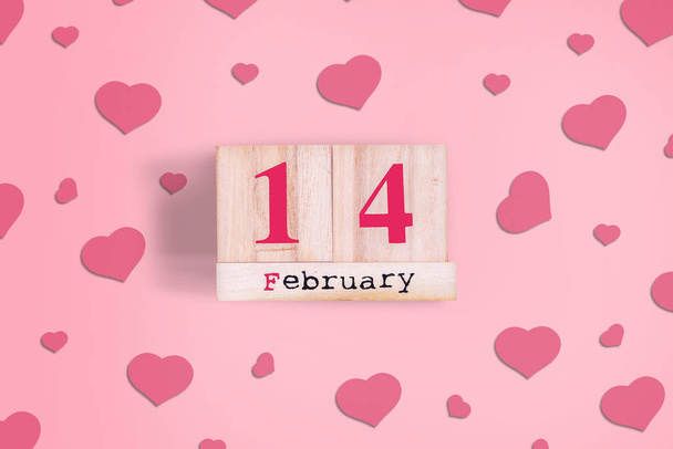 Op 14 februari. Houten kalender op een roze achtergrond met hartjes. Valentijnsdag achtergrond. - Foto, afbeelding
