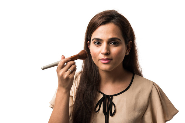 India joven mujer / chica poniendo maquillaje, de pie aislado sobre fondo blanco
 - Foto, imagen