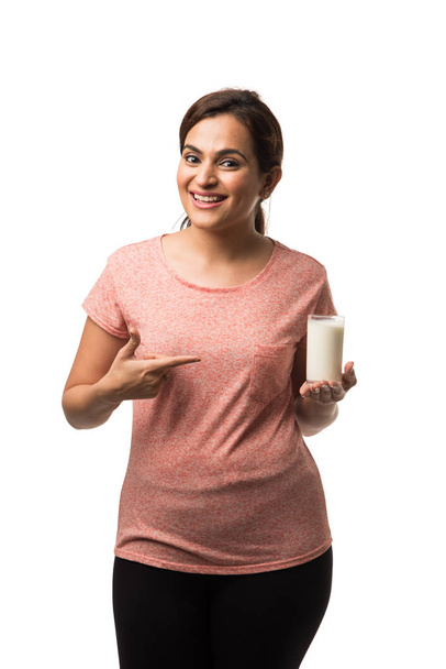 Porträt junge indisch / asiatische Frau trinkt Milch aus dem Glas isoliert über weißem Hintergrund - Foto, Bild