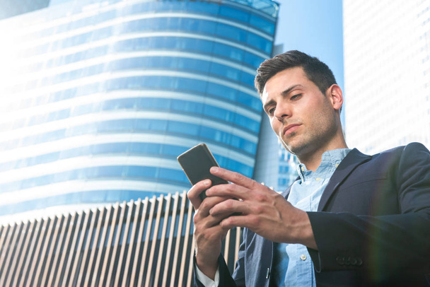 Крупним планом портрет серйозного бізнесмена, який дивиться на мобільний телефон у місті
  - Фото, зображення