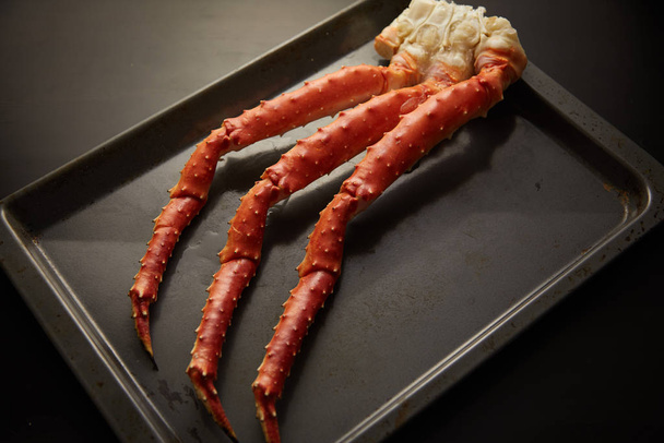 Image of fresh crab phalanges on oven-tray over dark background with copyspace - Photo, Image