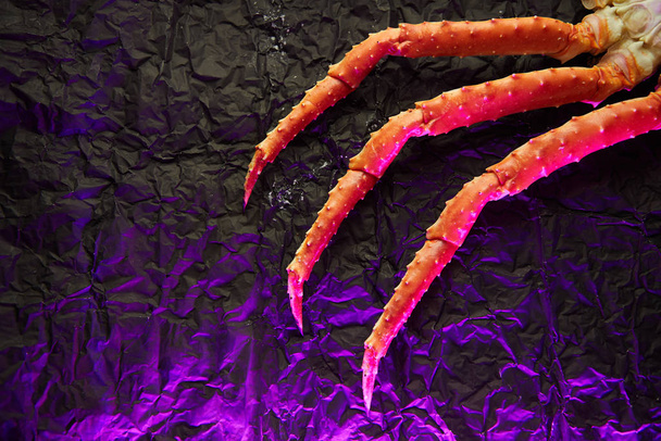 Imagem de falanges de caranguejo fresco no fundo escuro com copyspace em luz rosa
 - Foto, Imagem